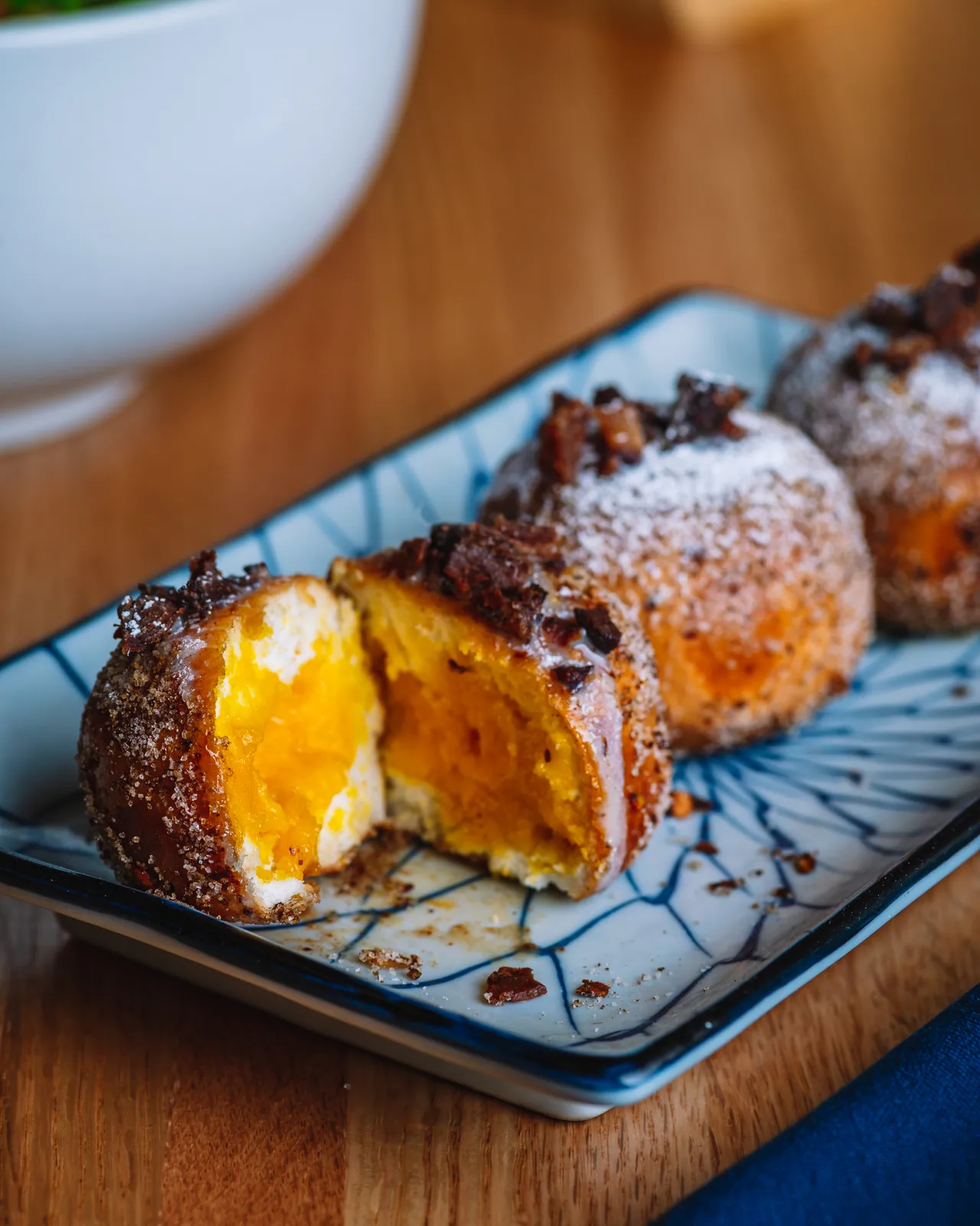 Sugar-coated golden dessert bites on a rectangular black plate