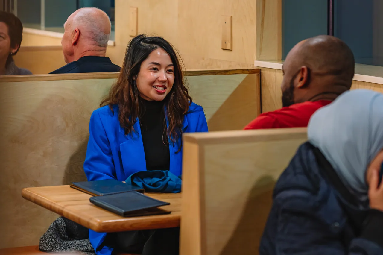 Two guests talking across a wooden dining table