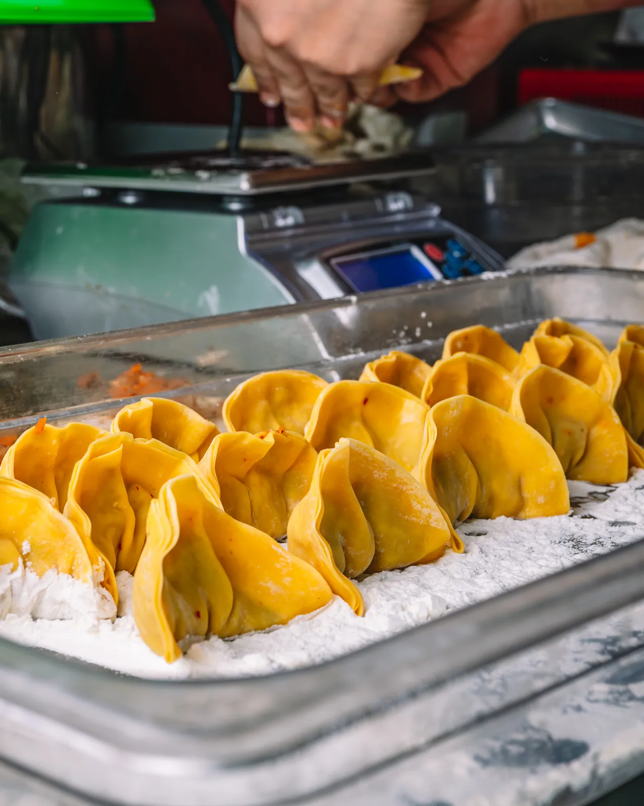 Rows of folded yellow dumplings on a kitchen tray