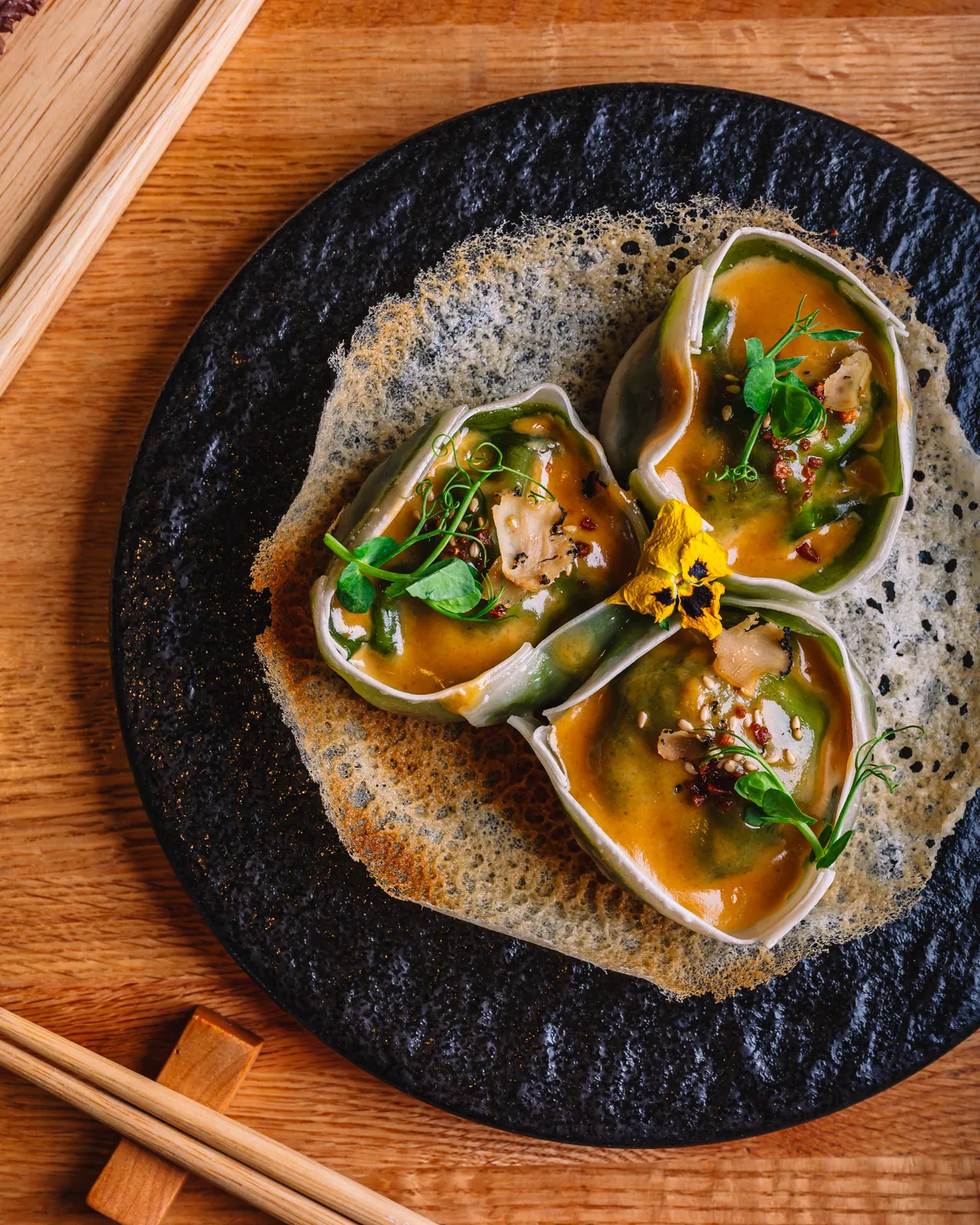 Three open dumplings topped with herbs on a round plate