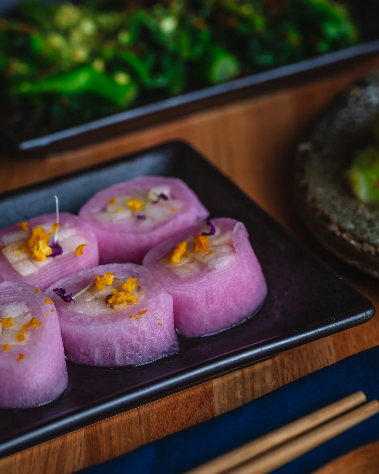 Purple small bites arranged on a black rectangular plate