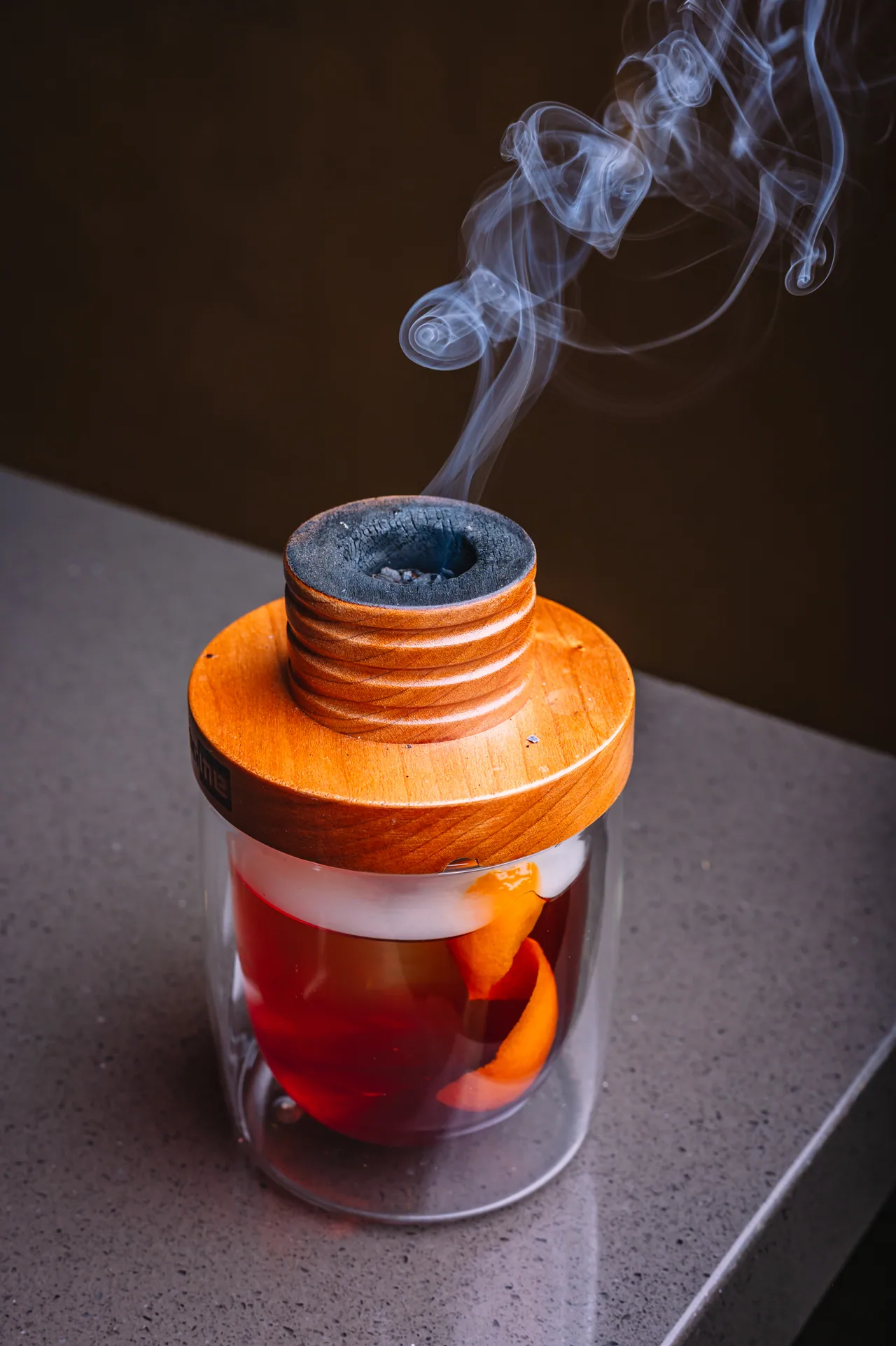 An amber drink beneath a smoking wooden lid