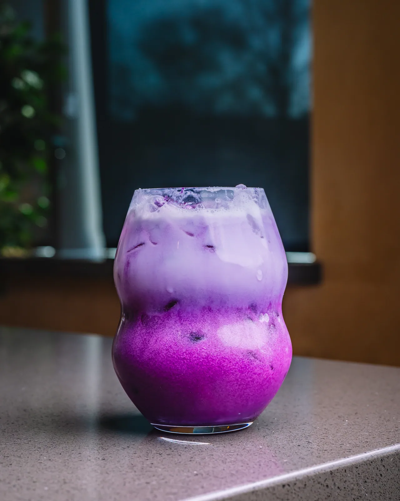 A violet iced drink with a pale top and purple garnish