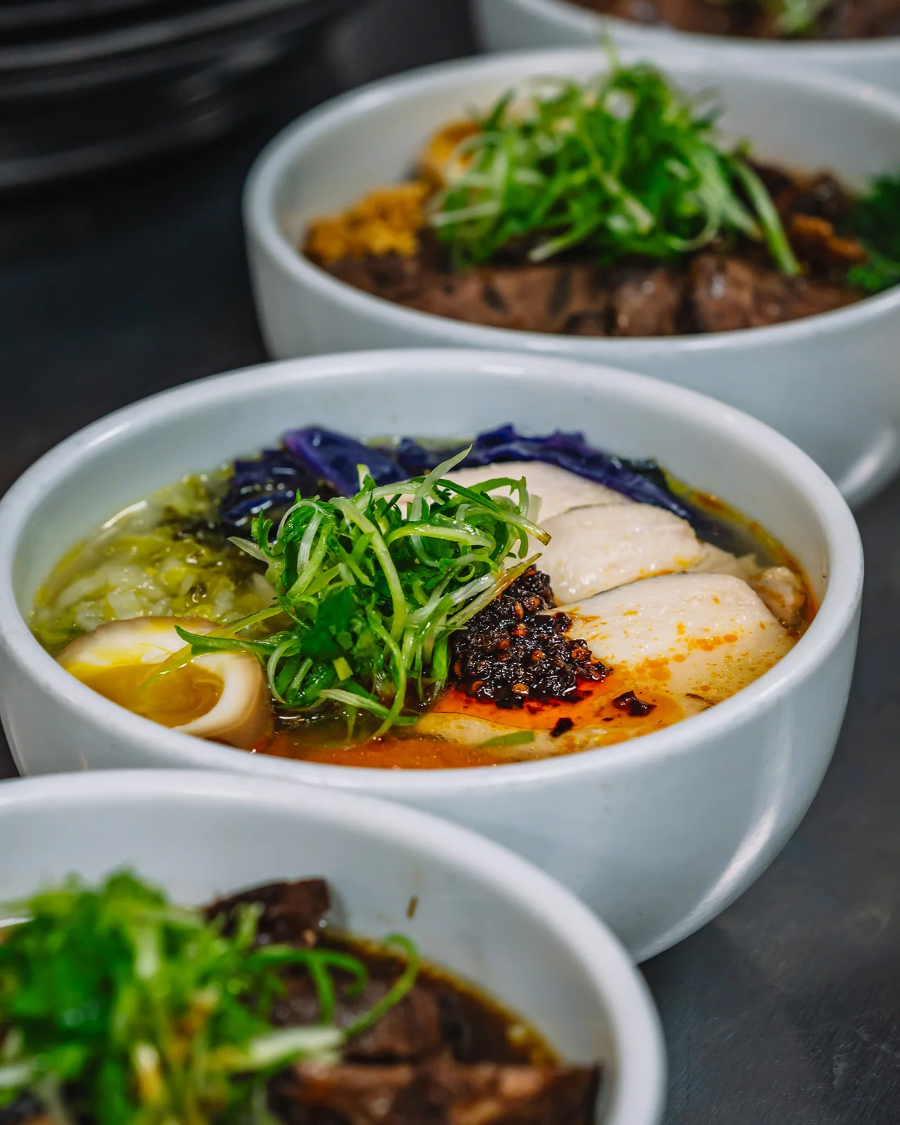 Bowls of noodle soup topped with greens and sliced garnishes
