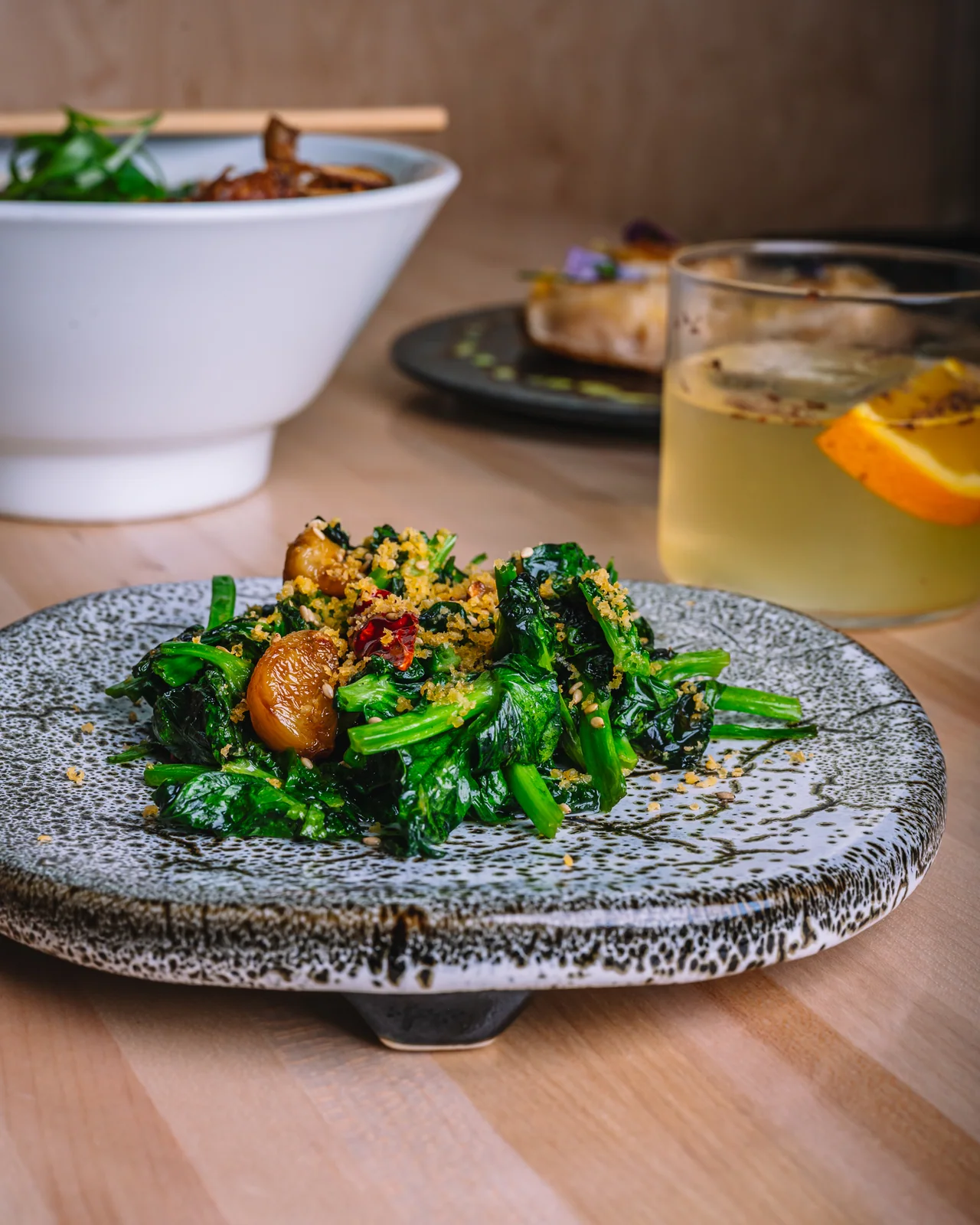 A plated small dish of greens with a crisp garnish
